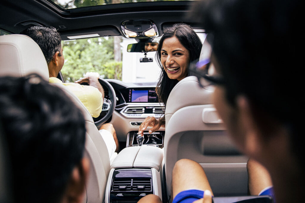 Woman looking back at children from front of an automotive